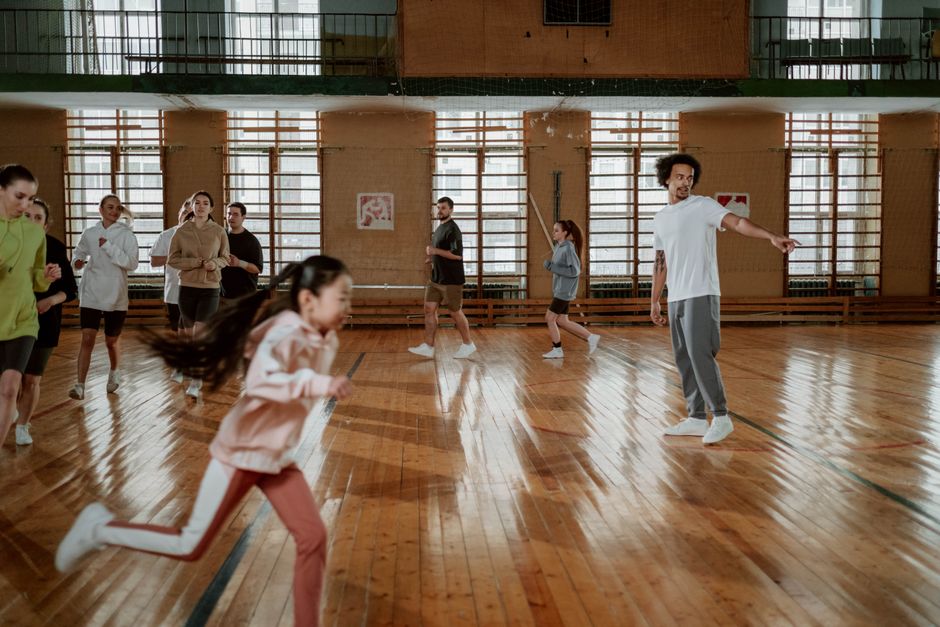 A diverse group of people running and training on an indoor basketball court with a wooden