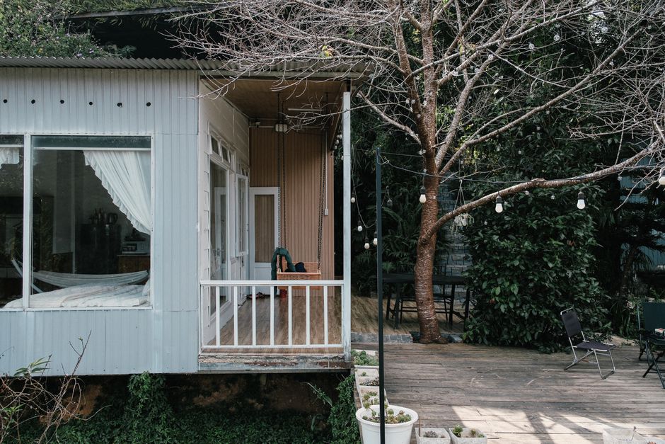 Charming cabin with a patio, surrounded by nature and a bare tree in winter setting.