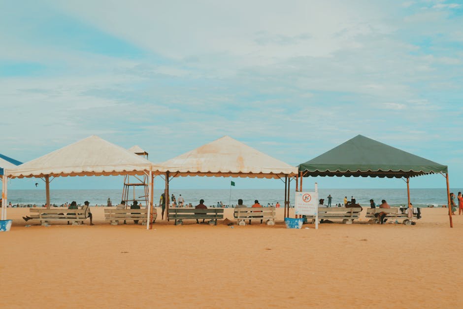 A tranquil beach scene with tents and benches, perfect for a relaxing day by the sea.