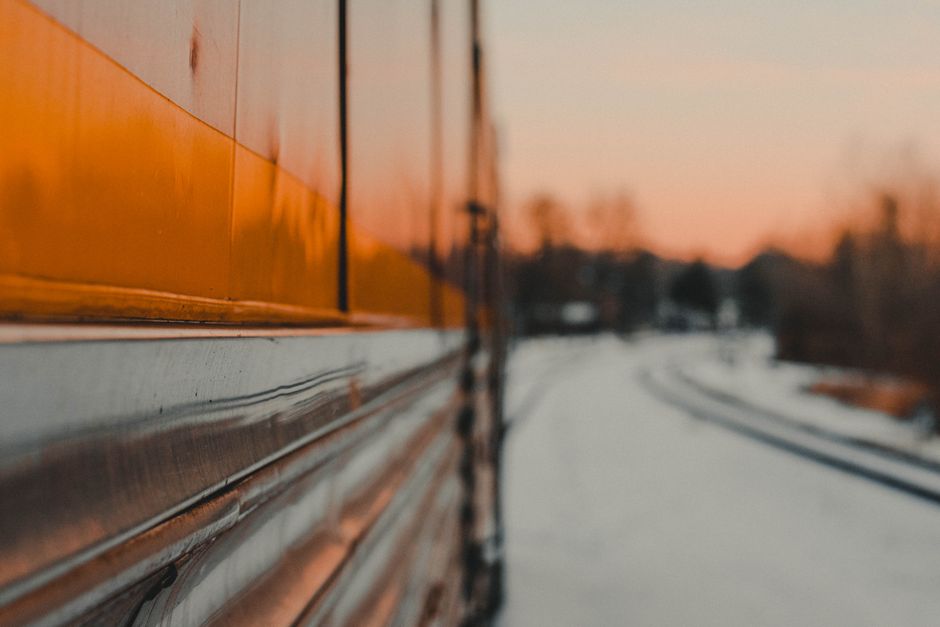 Blurred reflection of a train and snowy landscape in warm sunset light.