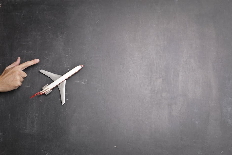 Top view of crop anonymous person indicating direction  on blank blackboard with miniature airplane