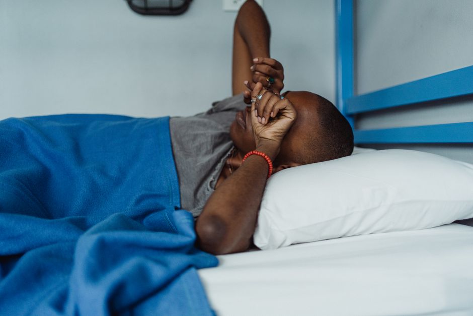Person relaxing in bed with a blue blanket, enjoying leisure and comfort.