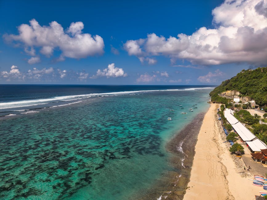 Breathtaking aerial view of a Bali beach, with turquoise waters and lush greenery.