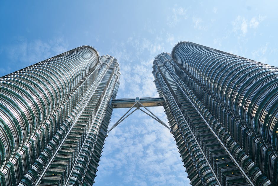 View of the iconic Petronas Twin Towers reaching towards a vibrant blue sky in Kuala Lumpur.