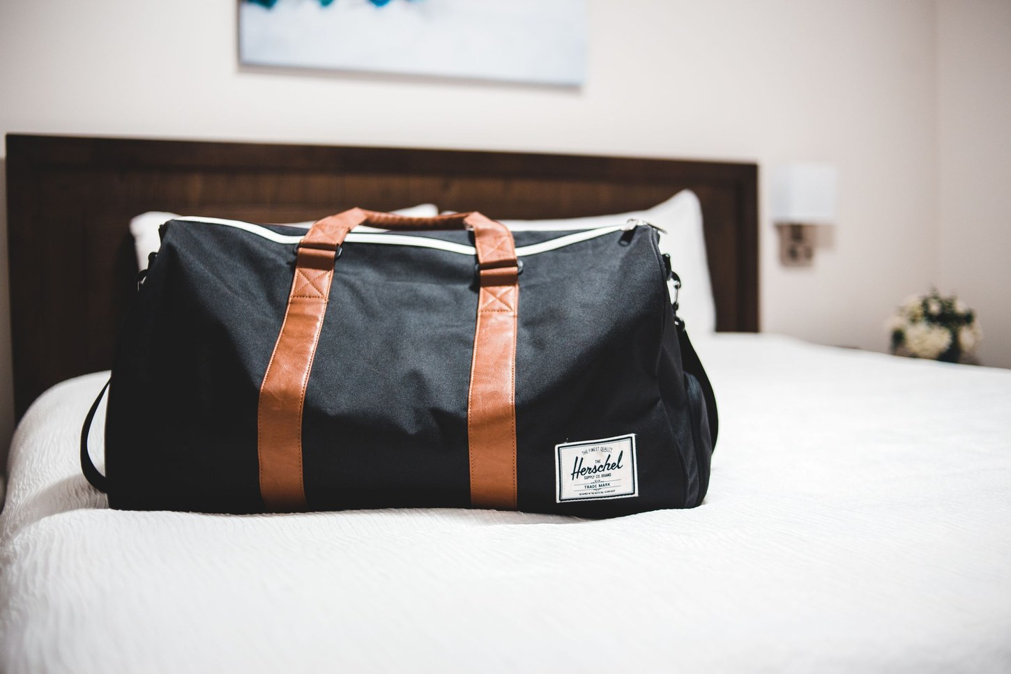 Black travel bag resting on a hotel bed
