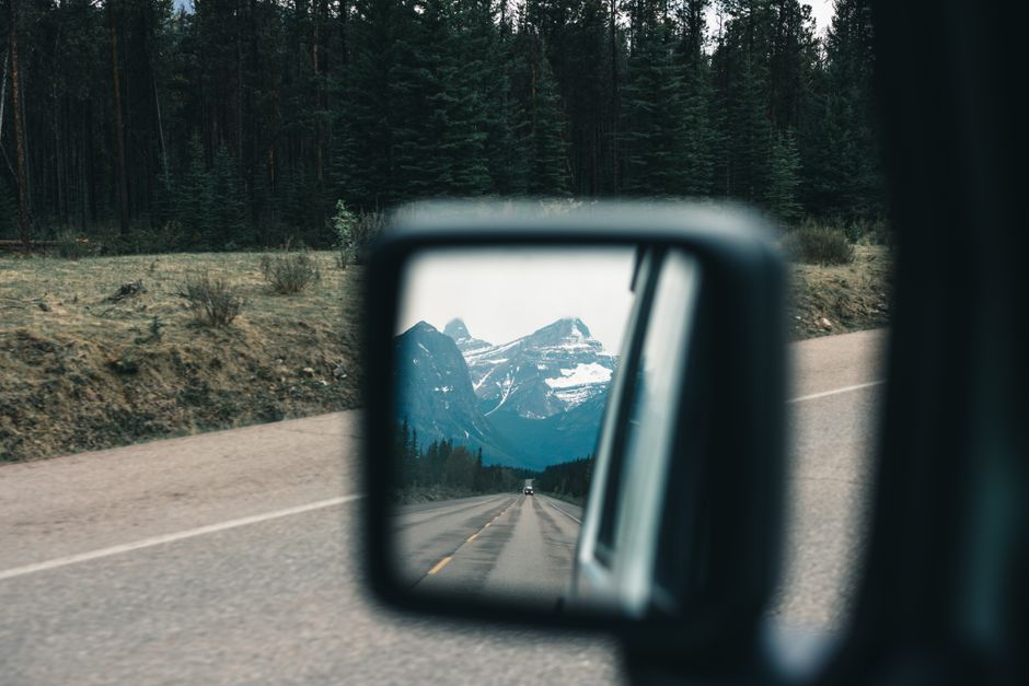 Stunning mountain view reflected in a car mirror on a forest road in Jasper, Canada.