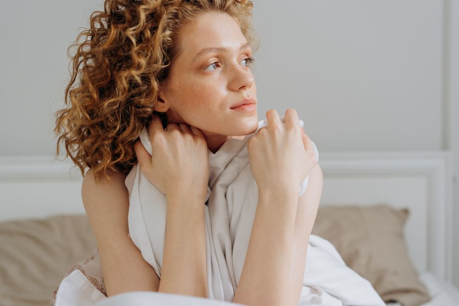 Serene moment of a young woman relaxing in bed, embracing calm and tranquility.