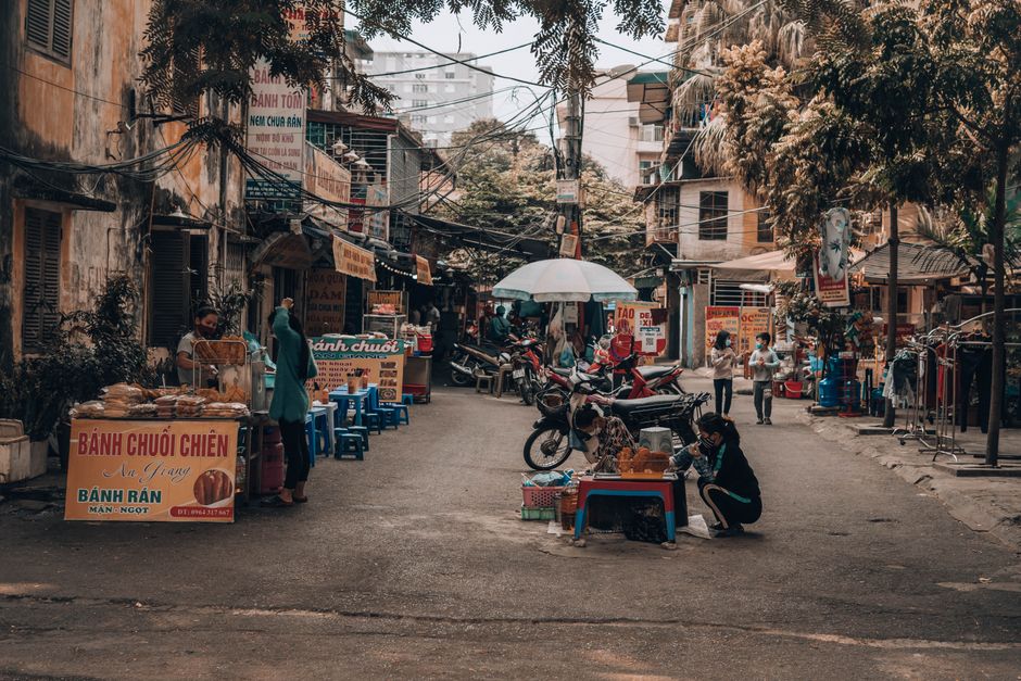 A bustling street food market in Vietnam with food stalls and people shopping. Captures the essence of street life.