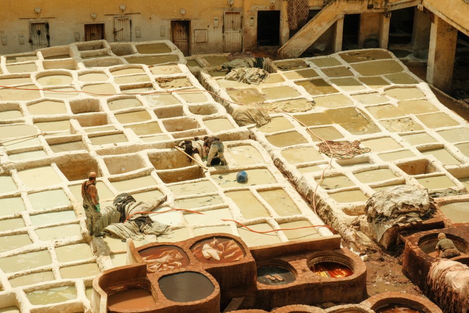 Aerial view of the historic leather tannery in Fes, showcasing traditional dyeing vats and workers.